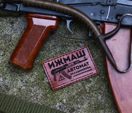 Leather Velcro patch with an image of a Kalashnikov AK47 laying next to a Century Arms Sar-2 AIMS74, which has a folded wire stock and leather stock pad.
